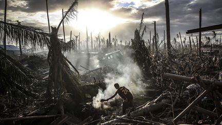 Un homme tente de faire un feu au milieu du paysage de d&eacute;solation cr&eacute;&eacute; par le passage du typhon Haiyan &agrave; Leyte (Philippines), le 19 novembre 2013. (DAN KITWOOD / GETTY IMAGES)