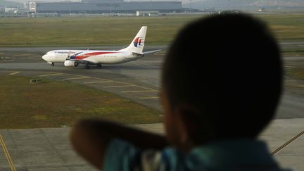 Un enfant regarde un avion de Malaysia Airlines décoller, le 25 juillet 2014. (OLIVIA HARRIS / REUTERS)