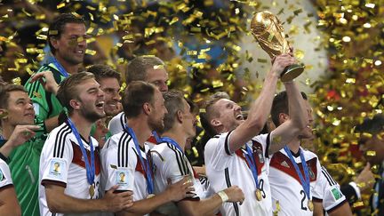 L'attaquant allemand André Schürrle brandit la Coupe du monde de football après la victoire de la&nbsp;Mannschaft sur l'Argentine en finale, le 13 juillet 2014 au stade Maracana de Rio (Brésil). Les Allemands avaient éliminés les Bleus en quart de finale. (ADRIAN DENNIS / AFP)