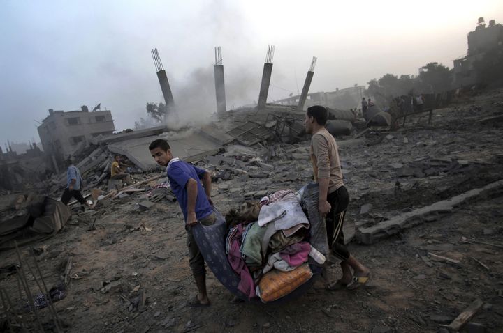 Des Palestiniens tentent de sauver quelques affaires des décombres de leur maison après une frappe aérienne israélienne pendant la nuit. Gaza, 8 juillet 2014. 
 (Khalil Hamra / The Associated Press)