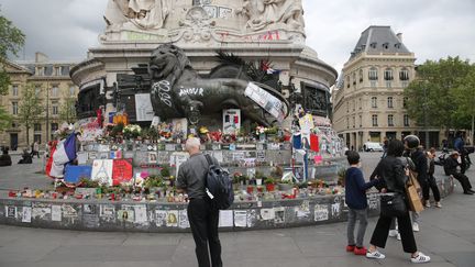 Des passants regardent les hommages et les graffitis laissés sur la statue de la place de la République, à Paris, le 12 mai 2016. (MAXPPP)