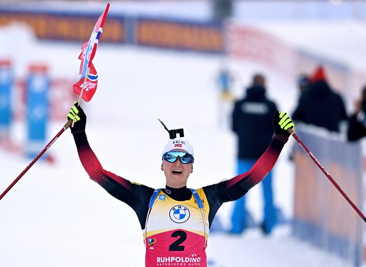 Marte Olsbu Roeiseland&nbsp;brandit le drapeau norvégien en franchissant la ligne lors de sa victoire sur la poursuite de Ruhpolding (Allemagne), le 16 janvier 2022. (CHRISTOF STACHE / AFP)