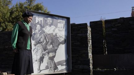 Une femme se tient en silence devant le mémorial sur lequel on peut voir une photo montrant Hector Pieterson, tué le 16 juin 1976 à Soweto.  (CORNELL TUKIRI / ANADOLU AGENCY)