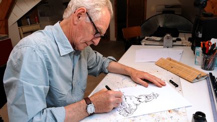 Le dessinateur René Pétillon dessine son personnage Jack Palmer, le 3 septembre 2013 à Nevez (Finistère). (FRED TANNEAU / AFP)