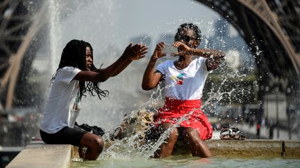 Deux personnes se rafraîchissent dans une fontaine au Trocadéro, à Paris, le 25 juillet 2018, lors d'une forte vague de chaleur. (BERTRAND GUAY / AFP)