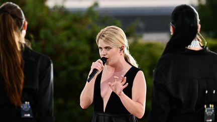 La soirée débute non pas au Stade de France mais dans le jardin des Tuileries où se trouve la vasque olympique. Zaho de Sagazan ouvre la cérémonie en interprétant "Sous le ciel de Paris", un hymne à la capitale écrit par Jean Dréjac et notamment chanté par Edith Piaf et Yves Montand. (LOIC VENANCE / AFP)