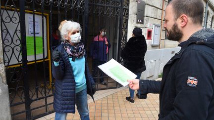 Une enseignante d'école élémentaire&nbsp;à Bordeaux explique à un parent d'élève les devoirs à faire à la maison pendant le confinement, le 17 mars 2020 (illustration). (NICOLAS TUCAT / AFP)