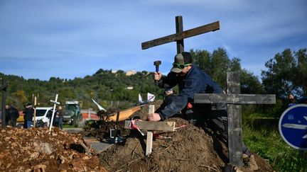 Sur un rond-point du Cannet-des-Maures, dans le Var, un agriculteur plante des croix pour dénoncer la "mort de l'agriculture française" face aux normes et aux taxes. (CHRISTOPHE SIMON / AFP)