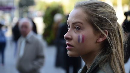 Le drapeau français peint sur la joue d'une jeune femme lors d'une minute de silence organisée devant la mairie de Madrid (Espagne). (PIERRE-PHILIPPE MARCOU / AFP)