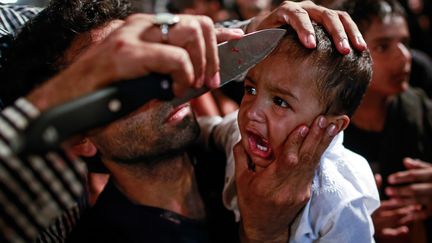 Un musulman chiite entaille le front de son fils lors de la traditionnelle procession de l'Achoura, &agrave; Bombay (Inde), le 3 novembre 2014. (DANISH SIDDIQUI / REUTERS)