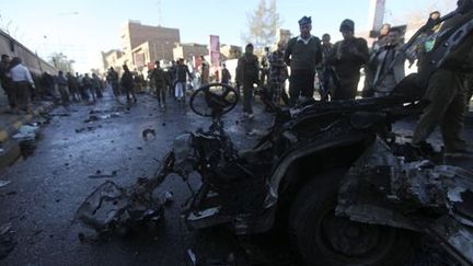 Des policiers observent les restes d'une voiture sur le site de l'attentat qui s'est produit devant l'académie de police à Sanaa le 7 janvier 2015.