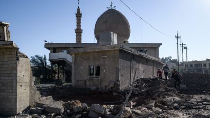 A Mossoul, en novembre 2016, des habitants passent devant une mosquee touchée par des frappes aeriennes dans un quartier du nord est de&nbsp;la ville irakienne. (MAXPPP)