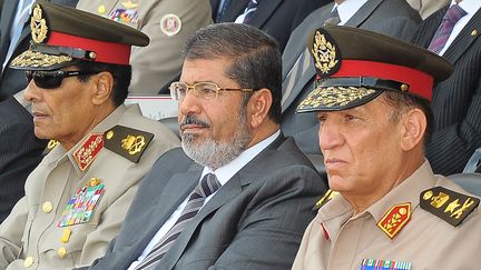 Le pr&eacute;sident Mohamed Morsi entour&eacute; d'Hussein Tantaoui (&agrave; gauche), et Sami Anan (&agrave; droite), tous les deux mis &agrave; la retraite par le chef de l'Etat, dimanche 12 ao&ucirc;t. (EGYPTIAN PRESIDENCY / AFP)