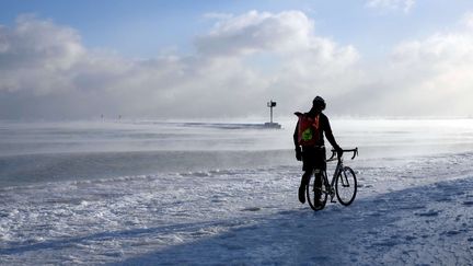 Un homme marche &agrave; c&ocirc;t&eacute; de son v&eacute;lo sur un sentier couvert de glace, pr&egrave;s du Lac Michigan, dans le nord des Etats-Unis, lundi 5 janvier 2015. (KIICHIRO SATO / AP / SIPA)