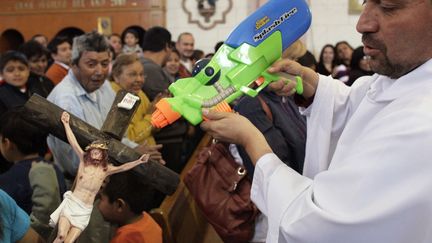 Un pr&ecirc;tre utilise un pistolet &agrave; eau pour asperger un crucifix d'eau b&eacute;nite lors d'une messe &agrave; Saltillo (Mexique), le 17 f&eacute;vrier 2013. (REUTERS)