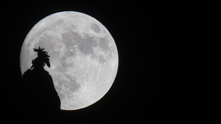 La "super Lune" visible derrière la statue de la liberté à Washington (Etats-Unis), le 13 novembre 2016. (ANDREW CABALLERO-REYNOLDS / AFP)