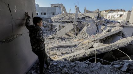 Un enfant observe les ruines d'un immeuble après une frappe israélienne, depuis le camp de Nuseirat, dans la bande de Gaza, le 12 novembre 2024. (MOIZ SALHI / MIDDLE EAST IMAGES / AFP)