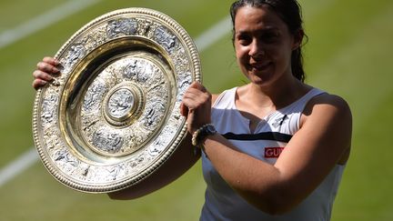 La tenniswoman Marion Bartoli brandit le troph&eacute;e de Wimbledon &agrave; Londres, le 6 juillet 2013. (CARL COURT / AFP)