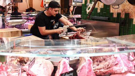 Un boucher découpe un morceau de viande dans un marché à Toulouse, le 14 octobre 2022. Photo d'illustration. (CHARLY TRIBALLEAU / AFP)