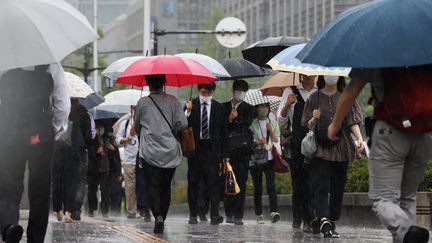 Des habitants se protègent de fortes pluies à Osaka, au Japon, le 2 juin 2023. (MAMI NAGAOKI / YOMIURI / AFP)