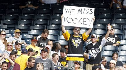 Un fan brandit un panneau sur lequel est écrit "Le hockey nous manque"