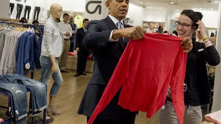 Le pr&eacute;sident am&eacute;ricain Barack Obama regarde un tee-shirt lors d'une vir&eacute;e shopping dans un magasin Gap &agrave; New York (Etats-Unis), le 11 mars 2014. Une fa&ccedil;on de rendre hommage &agrave; la marque&nbsp;qui a r&eacute;cemment augment&eacute; le salaire horaire de ses employ&eacute;s. (SAUL LOEB / AFP)