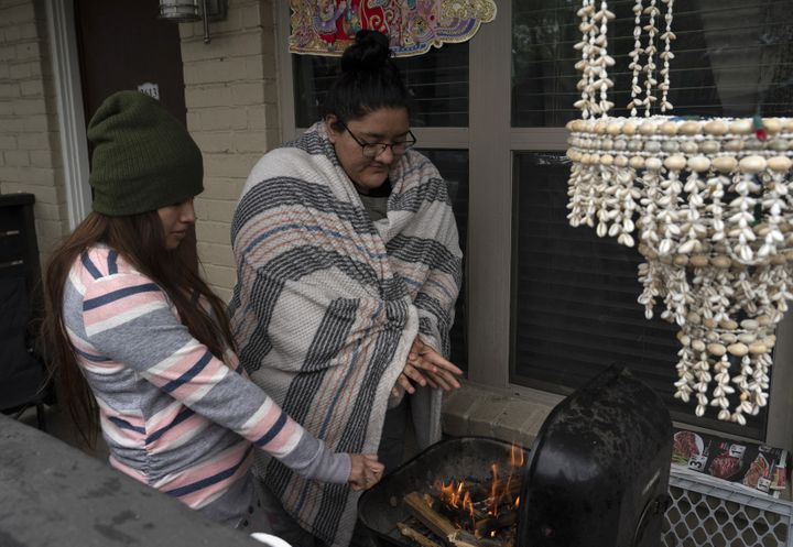 Deux Texanes tentent de se réchauffer autour d'un barbecue alors que l'Etat américain est balayé par une vague de froid qui a causé de nombreuses coupures de courant, à Houston (Etats-Unis), le 16 février 2021. (GO NAKAMURA / GETTY IMAGES NORTH AMERICA)