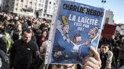 Un homme brandit la première page d'un hors-série de Charlie consacré à la laïcité, le 11 janvier 2015 lors de la marche républicaine à Lyon en hommage aux 17 victimes des attentats terroristes.
 (Jean-Philippe Ksiazek / AFP)