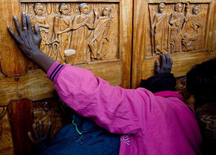 Une femme prie devant la porte du sanctuaire des martyrs ougandais à Namugongo, près de Kampala (Photo AFP/Marc Hofer)