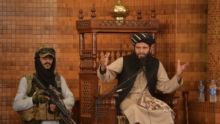 Un imam s'exprime aux côtés d'un combattant taliban lors de la prière du vendredi à la mosquée Abdul Rahman de Kaboul le 20 août 2021. (HOSHANG HASHIMI / AFP)