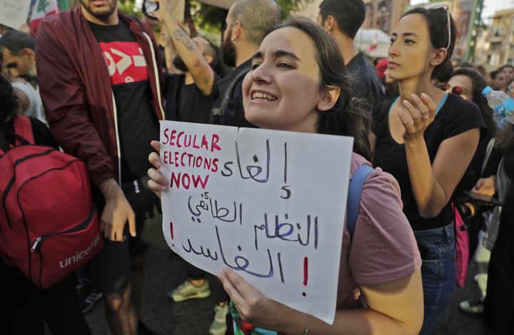 Une manifestante libanaise brandit une pancarte sur laquelle est inscrit&nbsp;"abolir le système sectaire corrompu", le 31 octobre 2019, à Beyrouth. (JOSEPH EID / AFP)