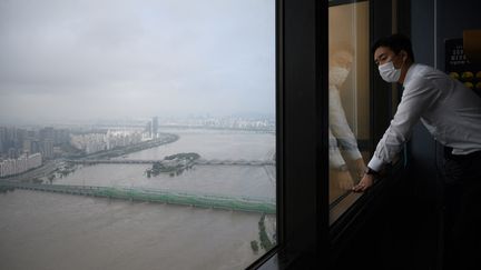 Un homme regarde la rivière Han gonflée par des fortes pluies au centre de Séoul (Corée du Sud), le 6 aout 2020. (ED JONES / AFP)