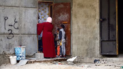 Une femme et ses enfants&nbsp;rentrent dans un appartement d' un immeuble abandonné&nbsp;du&nbsp;quartier de Tarik al-Sekka au centre de Tripoli, le&nbsp; 18 décembre 2019. (MAHMUD TURKIA / AFP)