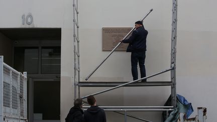 Des ouvriers installent une plaque commémorative en l'honneur des victimes des attentats du 7 janvier, sur la façade du 6-10, rue Nicolas-Appert, qui accueillait la rédaction de "Charlie Hebdo". (MAXPPP.)