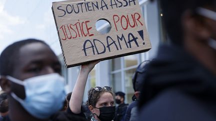 Un manifestant tient une pancarte "Soutien à Assa, justice pour Adama" devant le palais de justice de Paris, le 7 mai 2021. (THOMAS SAMSON / AFP)