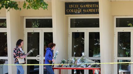 Des personnes déposent des fleurs devant le lycée Gambetta, à Arras (Pas-de-Calais), le 14 octobre 2023. (DENIS CHARLET / AFP)