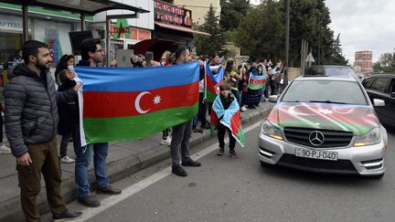 Des personnes tiennent le drapeau de l'Azerbaïdjan afin de célébrer, selon Bakou, la prise de la ville stratégique de Choucha dans le Haut-Karabakh, le 8 novembre 2020 à Bakou (Azerbaïdjan).&nbsp; (TOFIK BABAYEV / AFP)