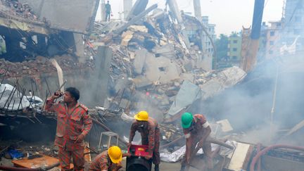 Les pompiers et secouristes continuent &agrave; enlever les corps et &agrave; aider les bless&eacute;s &agrave; Dacca&nbsp;(Bangladesh), le 29 avril 2013,&nbsp;apr&egrave;s l'effondrement d'un immeuble contenant plusieurs usines textiles le 24 avril. (MUNIR UZ ZAMAN / AFP)