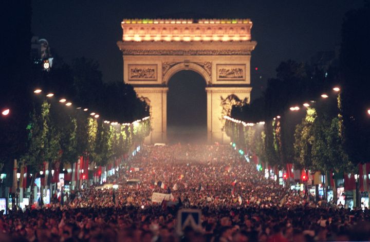 La foule réunie sur les Champs-Elysées pour célébrer l'équipe de France de football, le 8 juillet 1998, après la demi-finale de Coupe du monde entre la France et la Croatie au Stade de France. (JACK GUEZ / AFP)