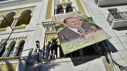 Un manifestant fait tomber un portrait géant du président algérien Abdelaziz Bouteflika à Alger, le 22 février 2019, lors d'une manifestation contre sa candidature à l'élection présidentielle. (RYAD KRAMDI / AFP)