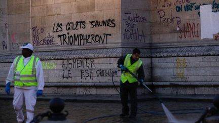 Des ouvriers nettoient les tags autour de l'Arc de Triomphe, à Paris, au lendemain de la mobilisation des "gilets jaunes", le 2 décembre 2018. (GEOFFROY VAN DER HASSELT / AFP)