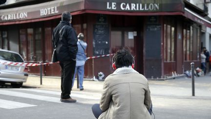 Une femme est assise devant le café "Le Carillon", le 14 novembre 2015, à Paris, à côté du restaurant cambodgien où des terroristes ont tué au moins 12 personnes, la veille. (KENZO TRIBOUILLARD / AFP)