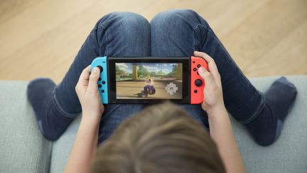 Un enfant avec sa console de jeux vidéo. (COLLANGES / BSIP)