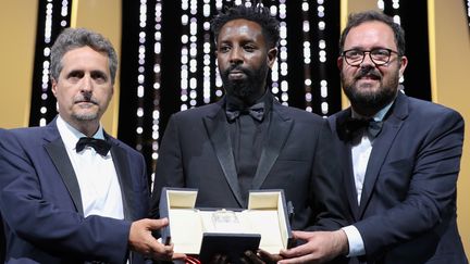 Ladj Ly (au centre) reçoit le Prix du Jury pour Les Misérables, ex-aequo avec les brésiliens Juliano Dormelles et Kleber Mendonça pour&nbsp;Bacurau (VALERY HACHE / AFP)