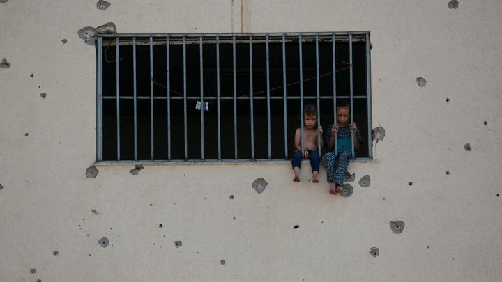 Des enfants palestiniens assis derrière les barreaux de l'ancienne prison centrale d'Asdaa dans la bande de Gaza, transformée en refuge, le 14 août 2024. (BASHAR TALEB / AFP)