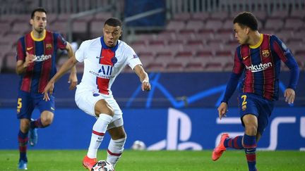 Le joueur du PSG Kylian Mbappé (centre) face à&nbsp;Sergino Dest, défenseur du FC Barcelone (droite), le 16 février 2021, lors du match aller de la Ligue des champions,&nbsp;au Camp Nou, à Barcelone (Espagne). (LLUIS GENE / AFP)