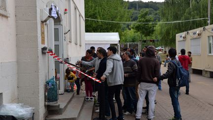 Des r&eacute;fugi&eacute;s attendent le 18 ao&ucirc;t 2015 devant un centre d'accueil de Tr&egrave;ves, en Allemagne. (HARALD TITTEL / DPA/AFP)