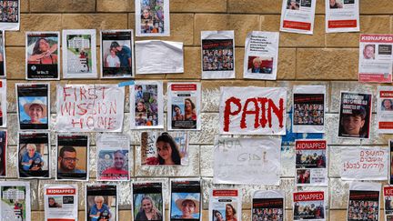 Posters showing Israelis missing since October 7, on a wall in Tel Aviv, October 18, 2023. (AHMAD GHARABLI / AFP)