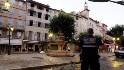 Un policier se tient devant l'immeuble qui a pris feu dans le centre-ville de Grasse (Alpes-Maritimes), le 13 août 2023. (JEAN FRANCOIS OTTONELLO / MAXPPP)