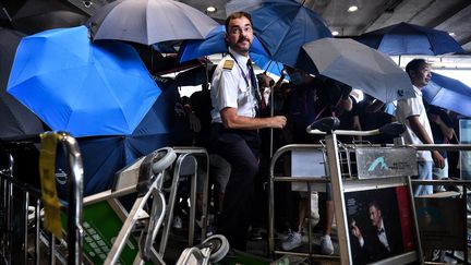 Un membre de l'équipage d'une compagnie aérienne&nbsp;tente de franchir une barrière&nbsp;érigée par des manifestants à l'aéroport international de Hong Kong, le 1er septembre 2019.&nbsp; (LILLIAN SUWANRUMPHA / AFP)